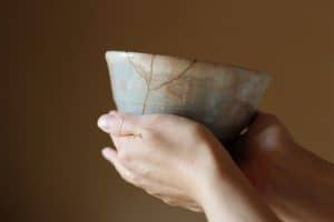 Repair of crack pottery tea cup with a hand